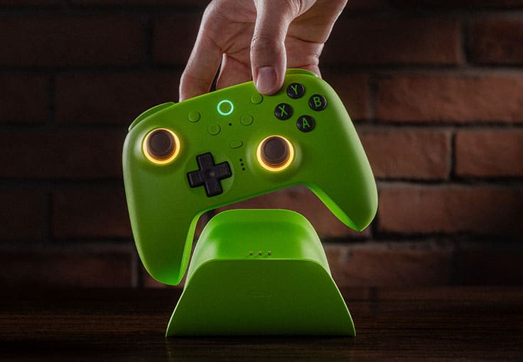 Green 8BitDo Ultimate 2 controller with glowing thumbsticks being lifted from its charging dock