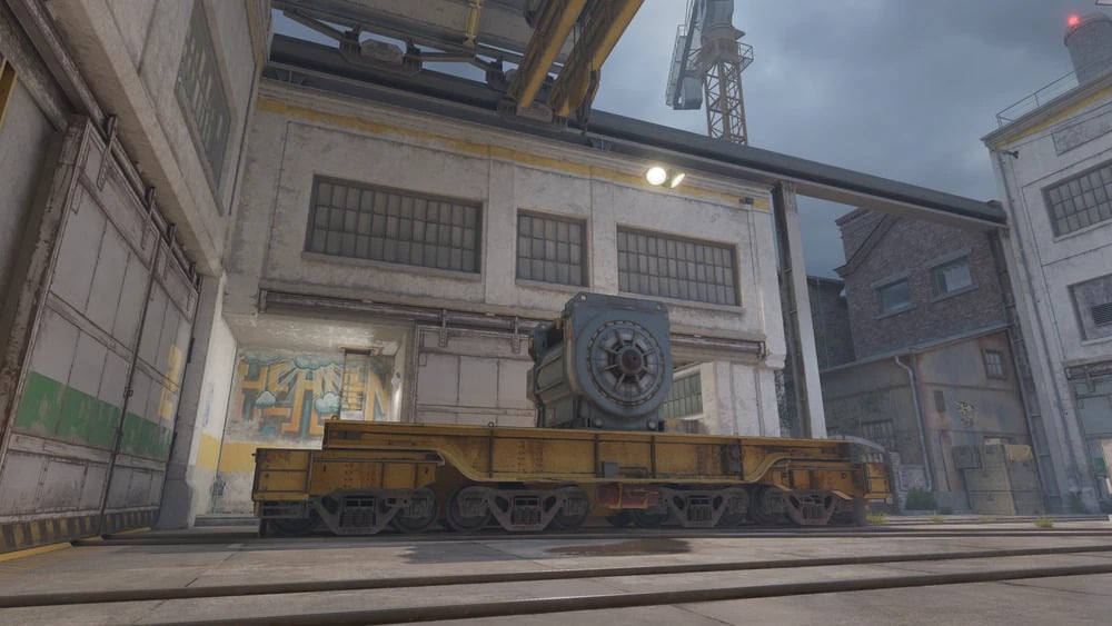 Industrial scene with a worn yellow rail cart carrying heavy machinery in CS2’s Train remake