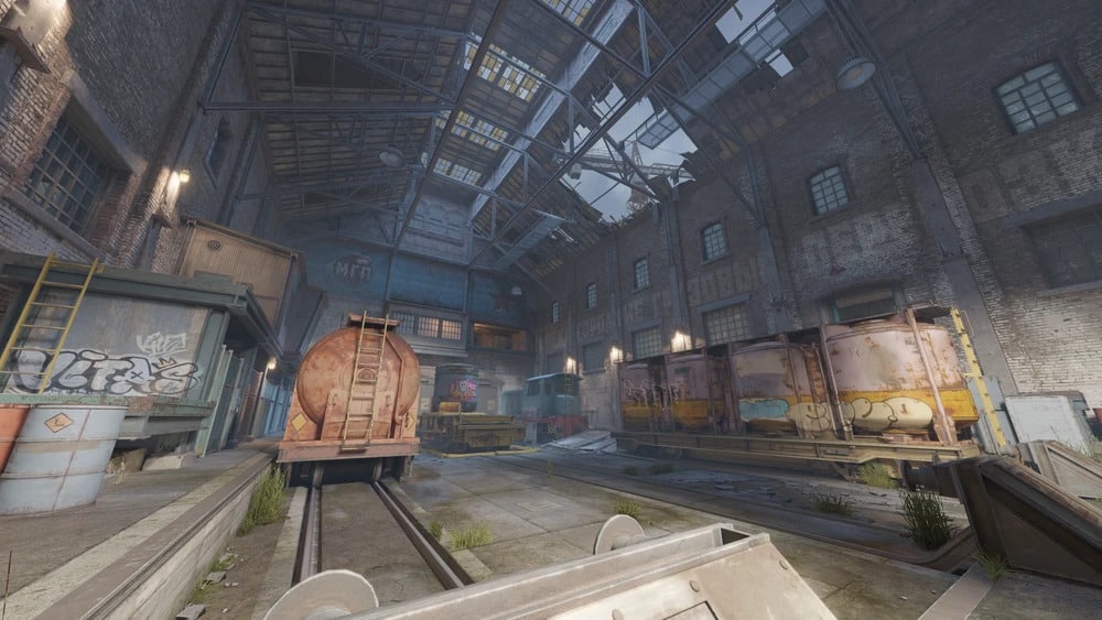 Abandoned train warehouse with graffiti-covered walls and rusted carts on tracks in CS:GO