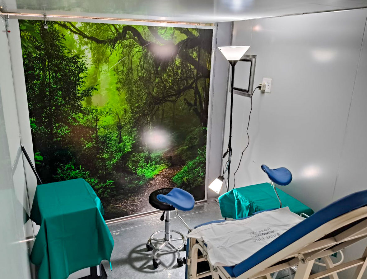 the interior of a trailer with an examination bench and stirrups opposite a beautiful woodland mural on the wall.