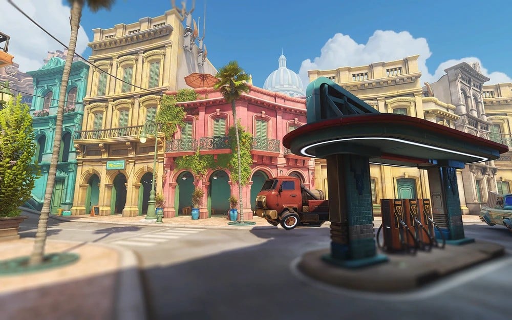 Colorful street scene featuring pastel buildings with arched windows, a vintage truck, and retro gas station under a clear blue sky with fluffy clouds