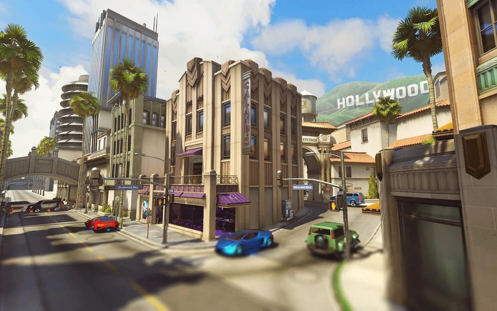 A sunny street scene with palm trees and various cars near an art deco building and "Hollywood" sign