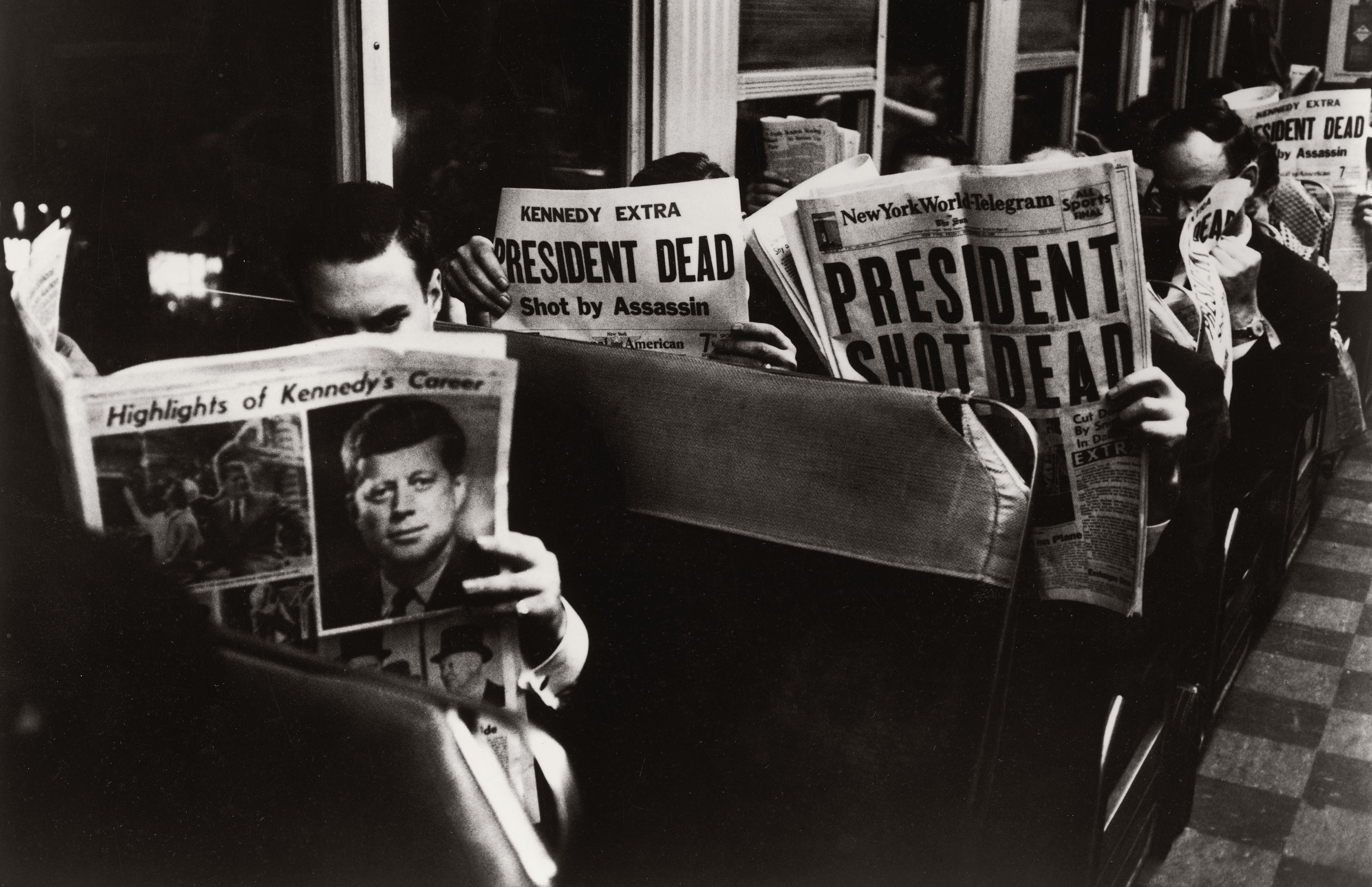 Commuters reading of John F. Kennedy's assassination in the newspaper